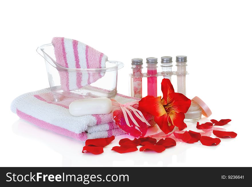 Spa essentials surrounded by rose petals on white background, reflective surface. Spa essentials surrounded by rose petals on white background, reflective surface