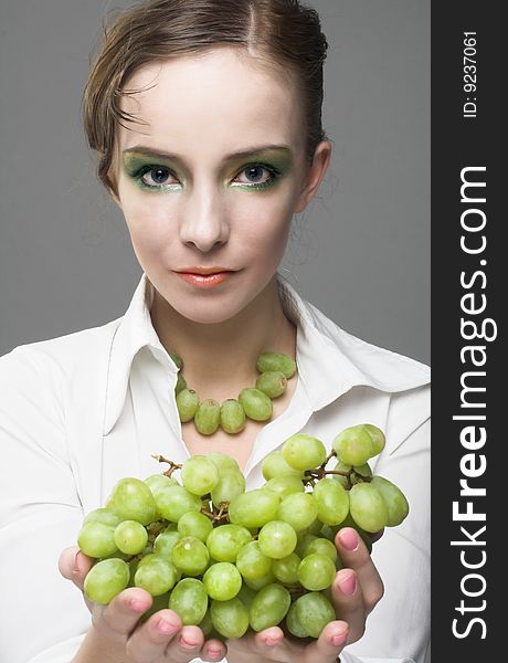 Portrait of young woman with green grapes
