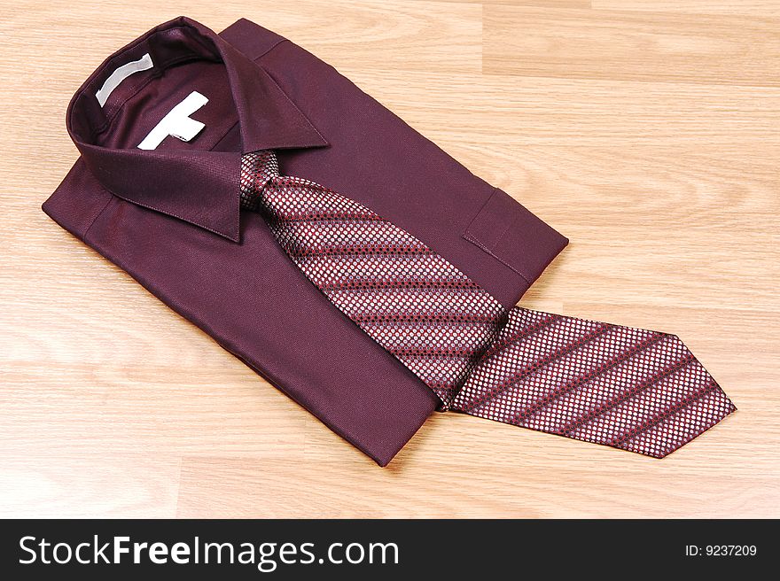 Burgundy dress shirt on a wood surface with an burgundy and beige tie
for sale in the store. Burgundy dress shirt on a wood surface with an burgundy and beige tie
for sale in the store.