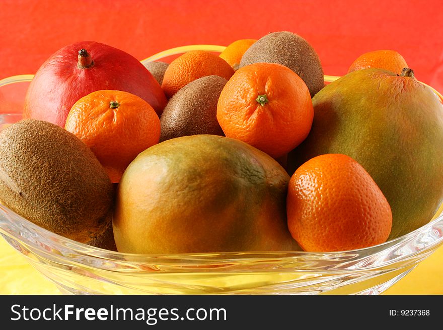 Crystal bowl full of mangos, kiwis, and clementines with colorful background. Crystal bowl full of mangos, kiwis, and clementines with colorful background