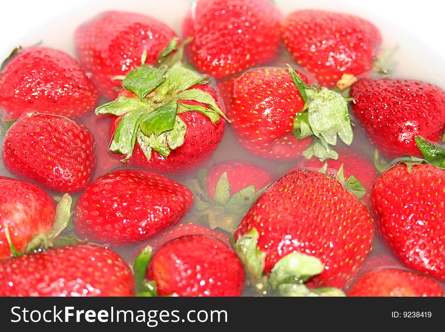 A macro shot of strawberries cleaning in a fruit wash. A macro shot of strawberries cleaning in a fruit wash.