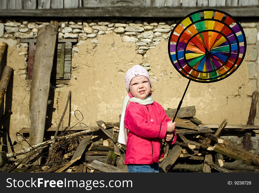A pretty  little   girl playing   on a background of an old  barn  in  the  countryside