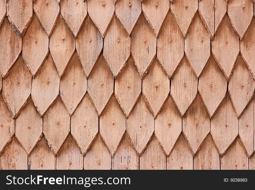 A part of a roof of an old house made of brown wooden tiles