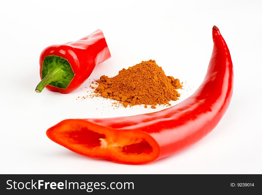 A composition of two  pieces of red chili  and  a  little  of  ground pepper  between  them on a white background