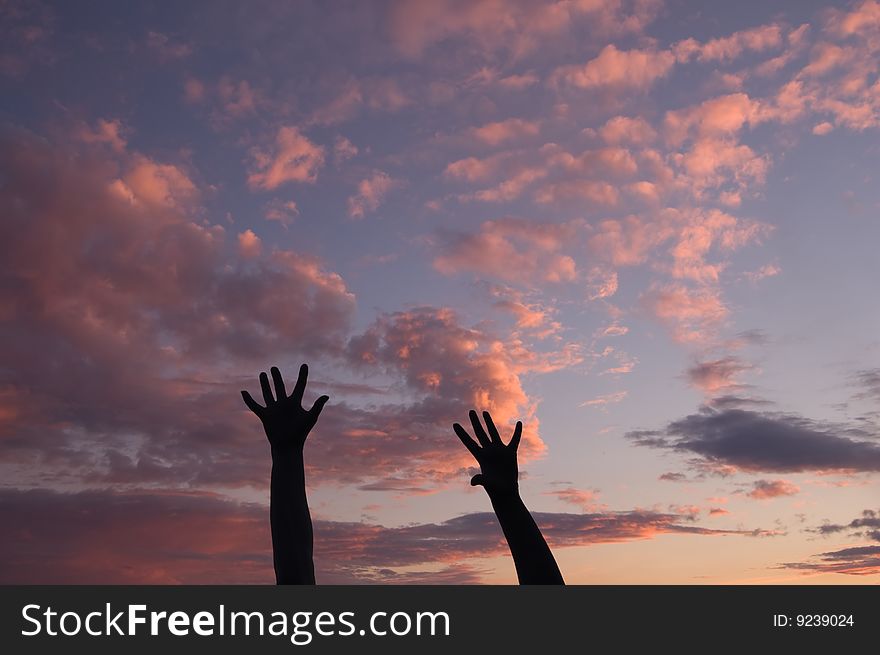 Silhouettes of two women's hands at sunset