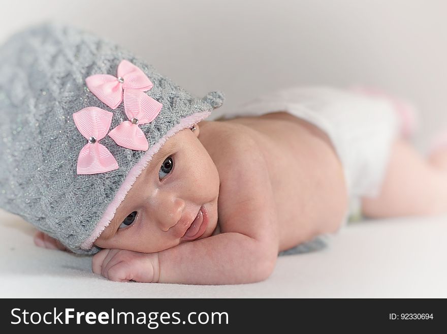 A newborn baby wearing a wool cap with pink bows. A newborn baby wearing a wool cap with pink bows.