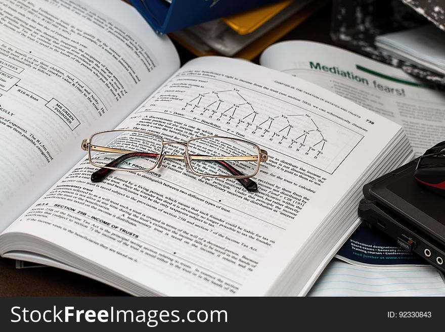 An opened textbook with eyeglasses on top. An opened textbook with eyeglasses on top.