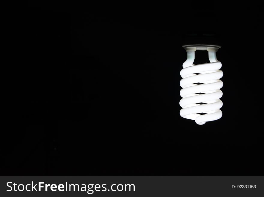 A spiral-shaped light bulb on black background. A spiral-shaped light bulb on black background.
