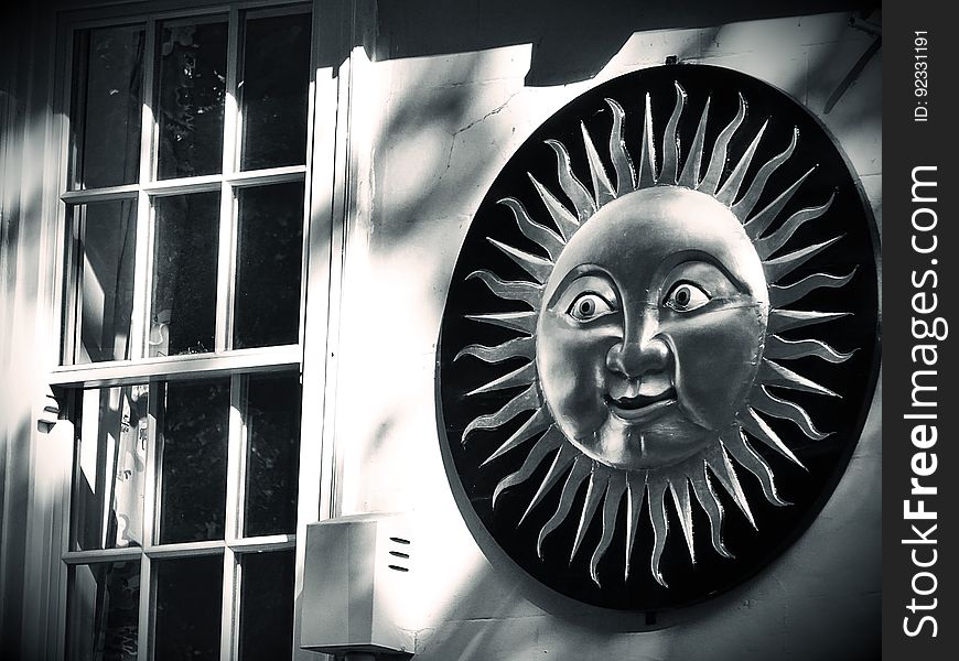 Detail of a house showing sash style window and beside it on the wall a circular decoration symbolizing the smiling sun. Detail of a house showing sash style window and beside it on the wall a circular decoration symbolizing the smiling sun.