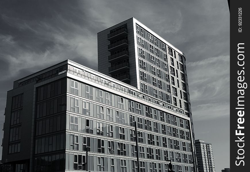 Apartments or office blocks with rectangular shape lacking decoration and with repeated features on a gray day with glowering sky. Apartments or office blocks with rectangular shape lacking decoration and with repeated features on a gray day with glowering sky.