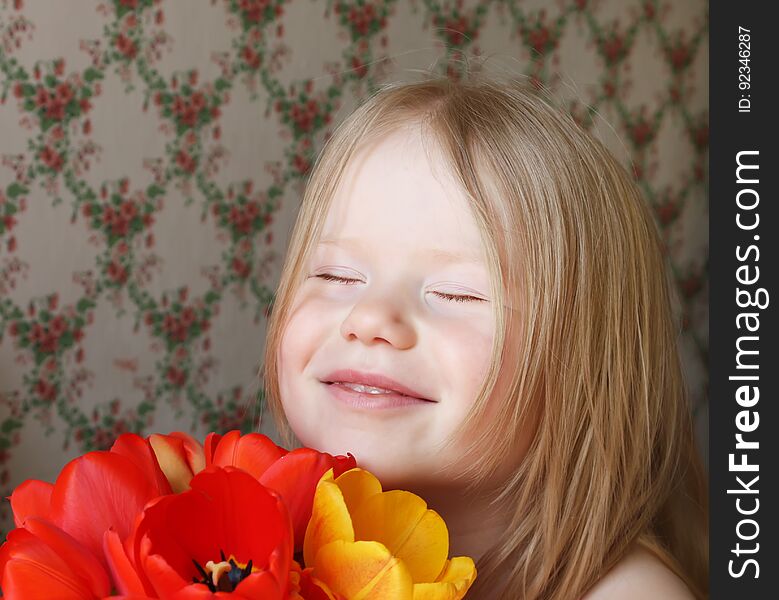 A little smiling girl with red and yellow tulip flowers. A little smiling girl with red and yellow tulip flowers