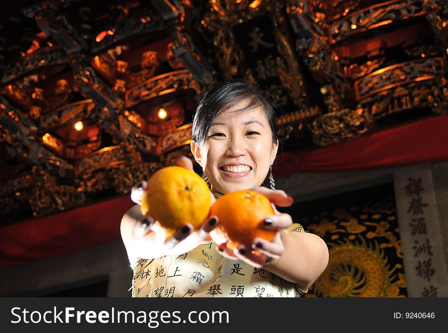 Beautiful Asian woman in cheongsam holding two oranges, suitable for Chinese New Year occasion. Beautiful Asian woman in cheongsam holding two oranges, suitable for Chinese New Year occasion.