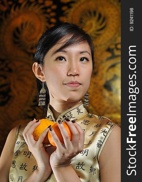 Beautiful Asian woman holding oranges in oriental theme. Suitable for Chinese New Year occasion. Beautiful Asian woman holding oranges in oriental theme. Suitable for Chinese New Year occasion.
