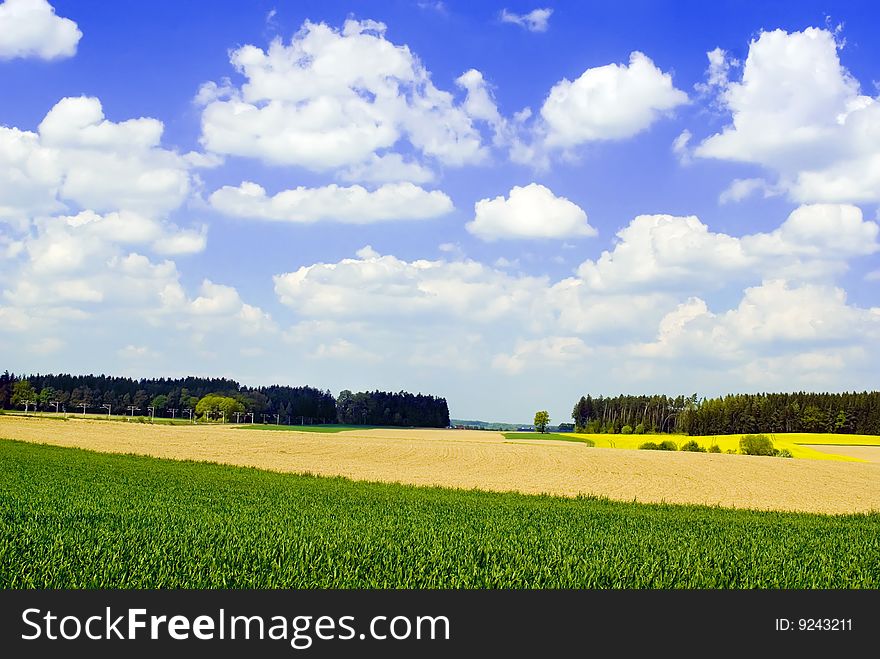 A image of a countryside landscape with clouds on a blue sky. A image of a countryside landscape with clouds on a blue sky