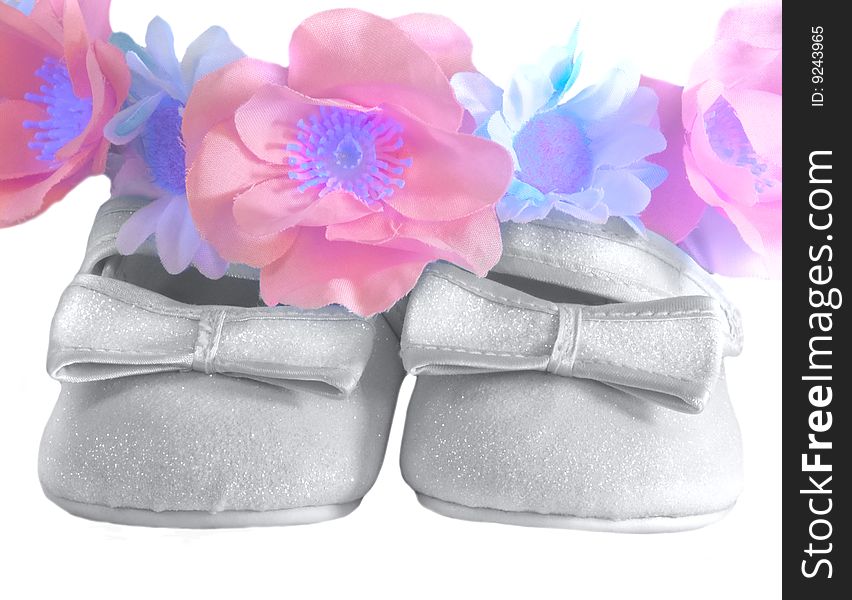 Children's silver shoes with bows and a wreath from colours close up. Children's silver shoes with bows and a wreath from colours close up