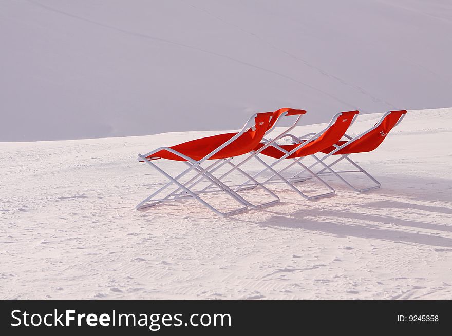 Three Red Deckchairs in the Swiss Alps, sitting on fresh snow in the sunshine. Three Red Deckchairs in the Swiss Alps, sitting on fresh snow in the sunshine.