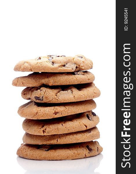 Vertical image of a stack of 7 chocolate chip cookies on a white reflective surface. Vertical image of a stack of 7 chocolate chip cookies on a white reflective surface