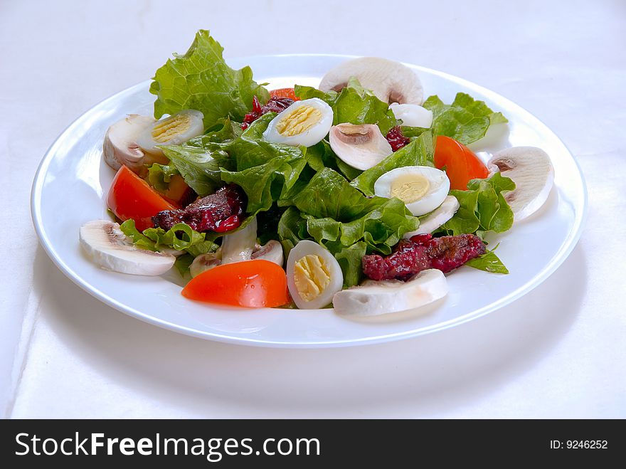 Salad of fresh mushrooms, eggs and tomatoes, decorated with leaves of lettuce