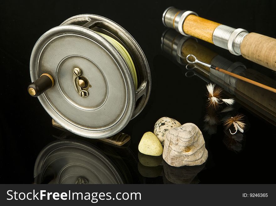 Still life of old fly reel with some flies with a bamboo rod and stones