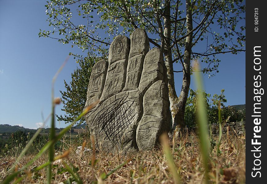 A hand of stone emerges from the field.