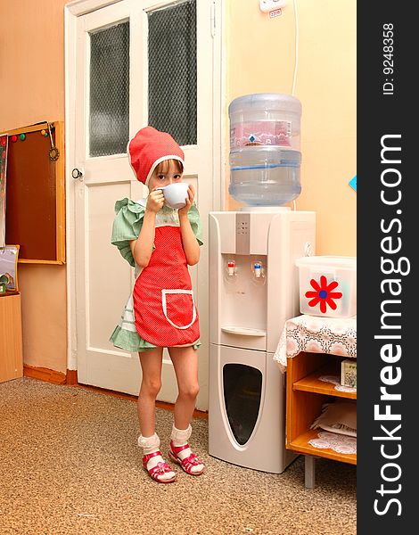 The girl drinks water from the drinking automatic machine