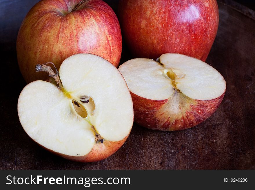 Three apples one cut open on dark background