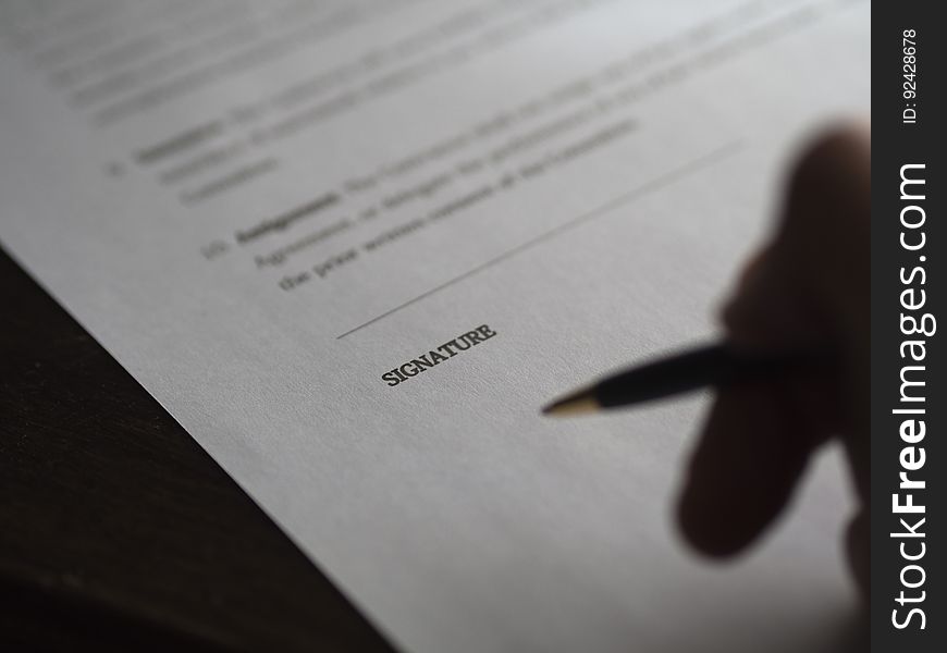 Closeup of a person signing paperwork.