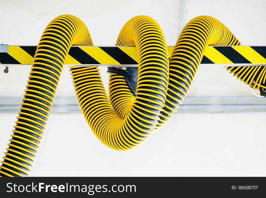 A black and yellow hose wrapped around a post.