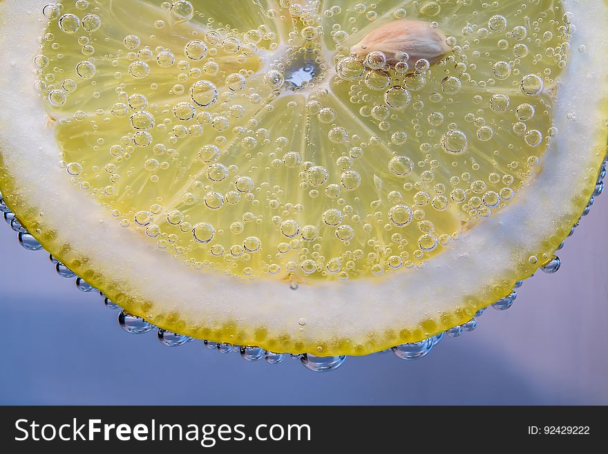 A slice of yellow lemon in a glass of carbonated water. A slice of yellow lemon in a glass of carbonated water.