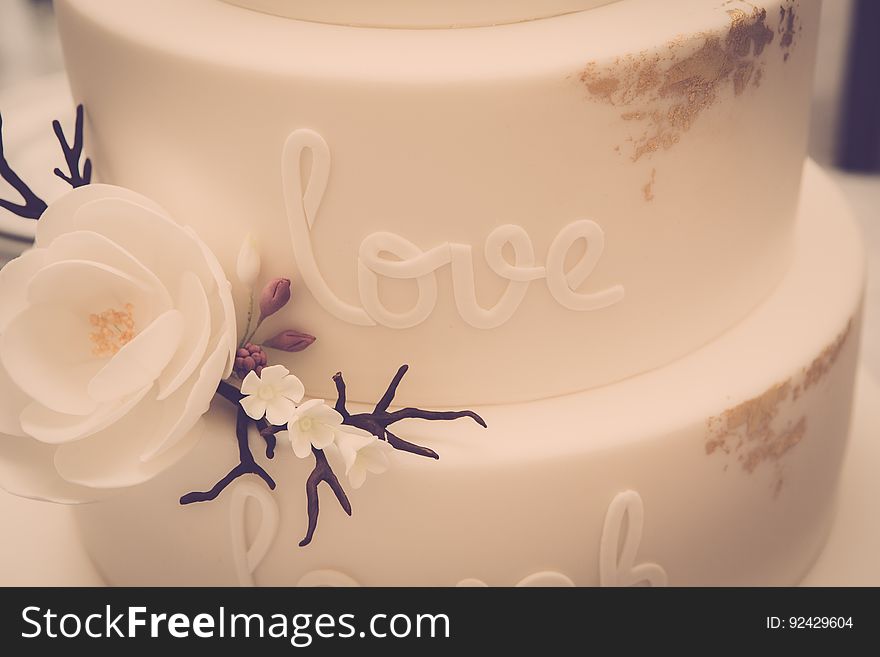 A white fondant cake with the writing "love" on the side.