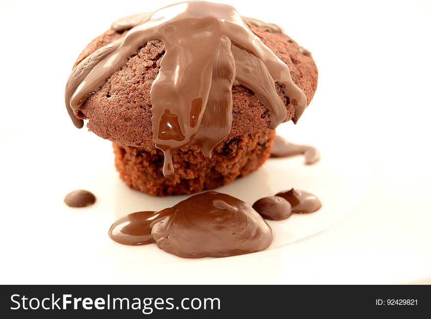 A rich chocolate muffin with chocolate icing isolated on white.