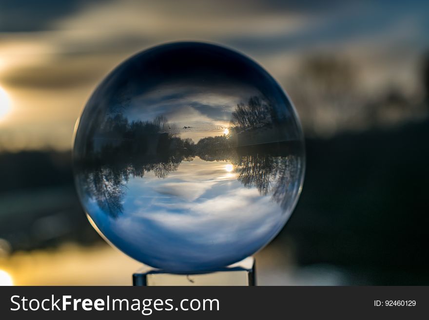 A crystal ball refracting the light with the sunset on the background.