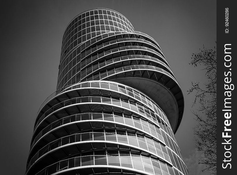 Black and white view looking to top of curved tall modern office tower building. Black and white view looking to top of curved tall modern office tower building.