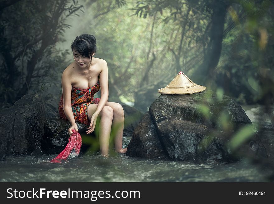 Asian Woman Washing Clothes In Stream