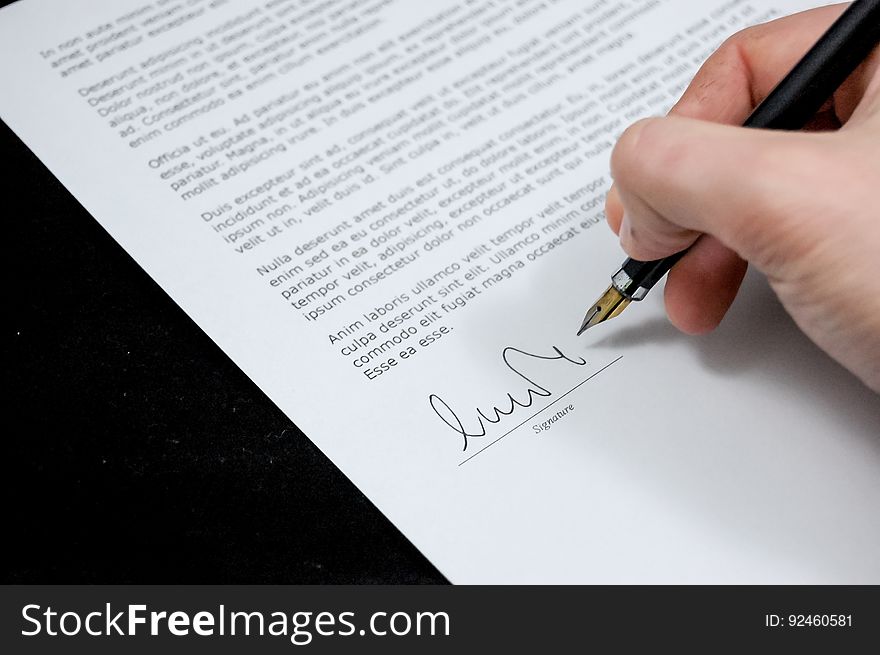 The hand of a person signing an agreement with a fountain pen. The hand of a person signing an agreement with a fountain pen.