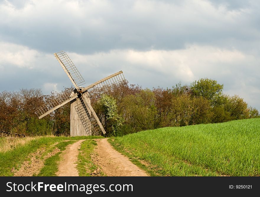 The old windmill to stand on a green field near wood