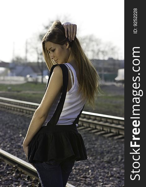 Young brunette girl standing on the railroad