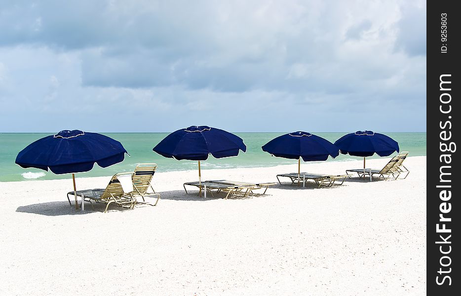 A group of lounge chairs and parasols on a perfect white sand beach. A group of lounge chairs and parasols on a perfect white sand beach