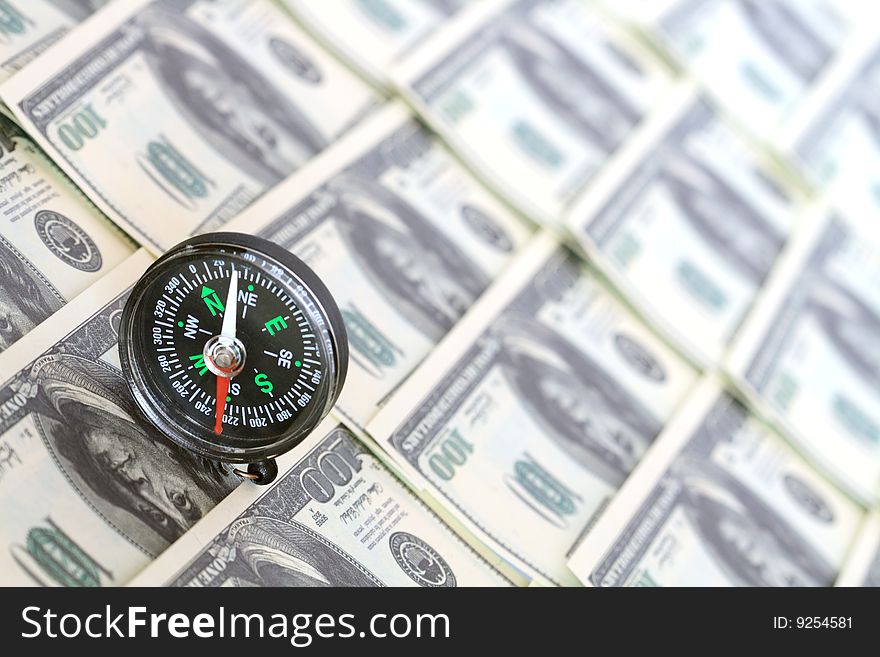 Compass standing on background with one hundred dollar banknotes. Compass standing on background with one hundred dollar banknotes