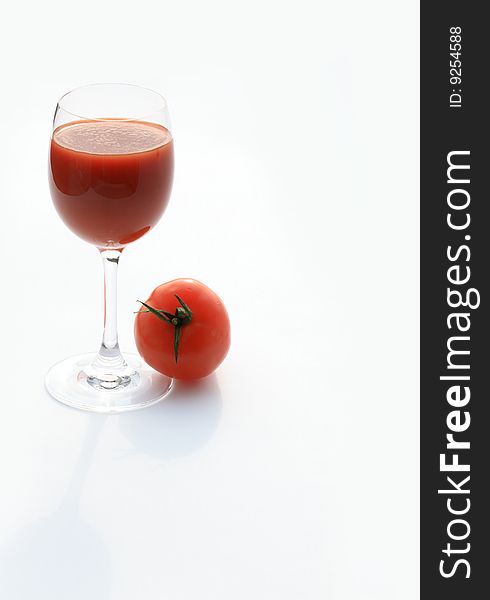 Tomato lying near goblet of tomato juice isolated on white background