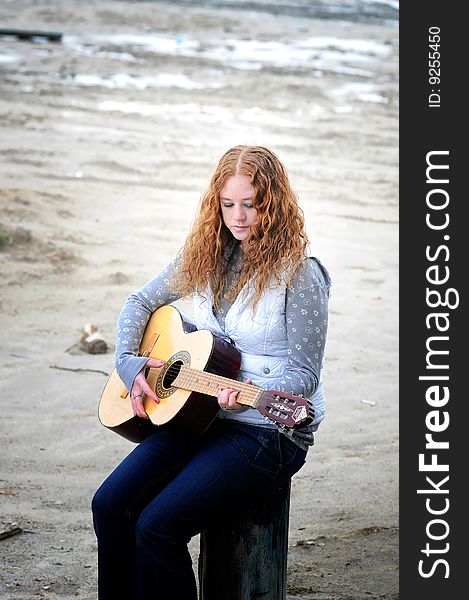 A girl with her guitar sitting on the beach. A girl with her guitar sitting on the beach