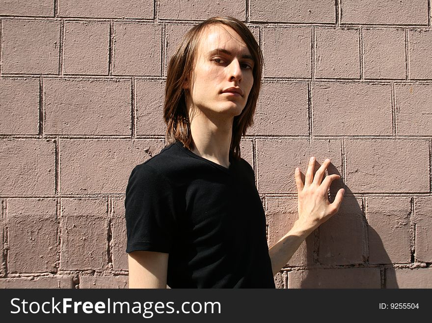Sexy man standing in front of a brick wall