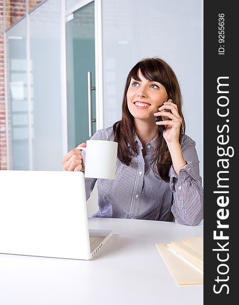 Business Woman on a cell phone and laptop in modern office
