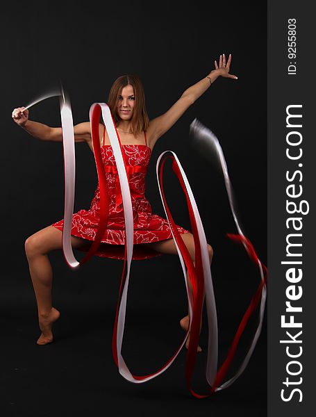 Elegant young flexible woman in red-white outfit with two ribbons