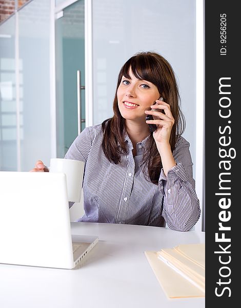 Business Woman on a cell phone and laptop in modern office