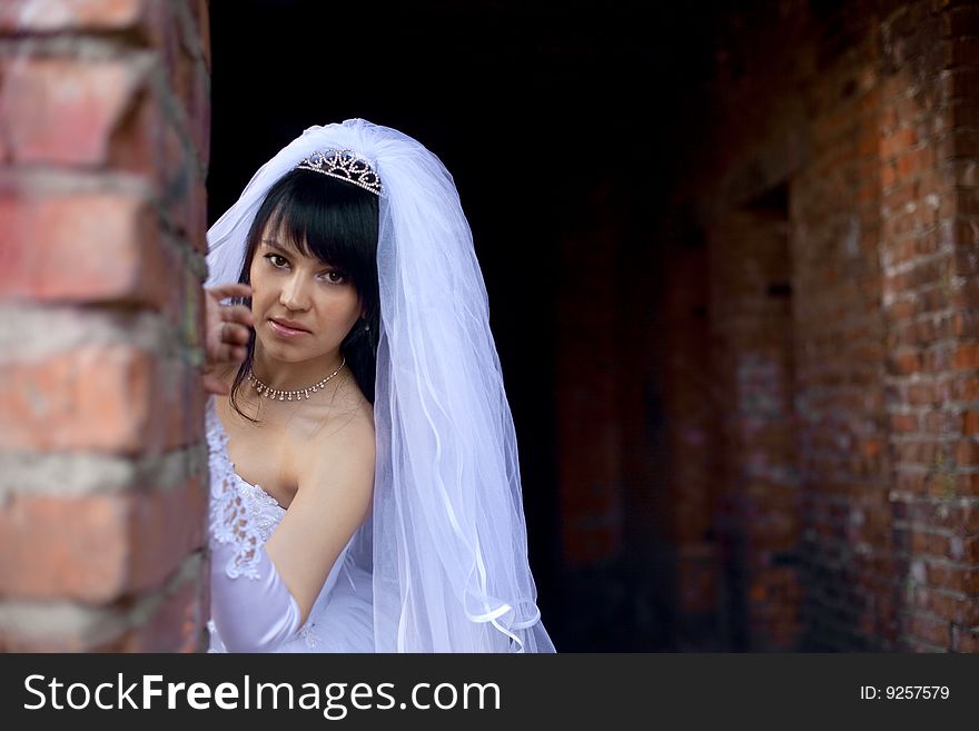 Pretty bride stand up near wall