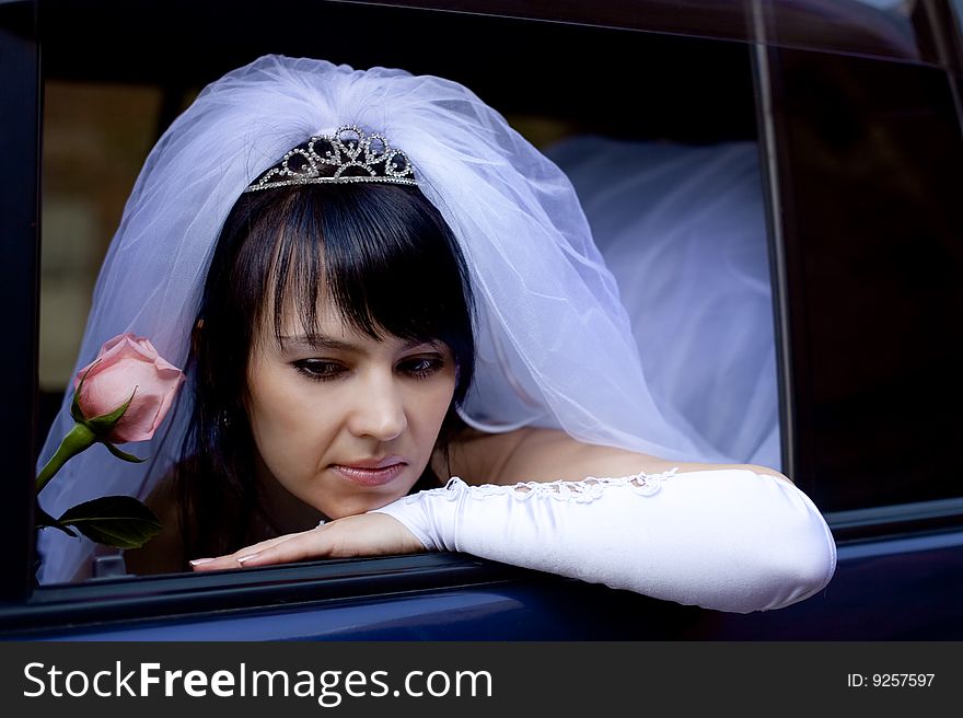 Pretty bride with rose in car