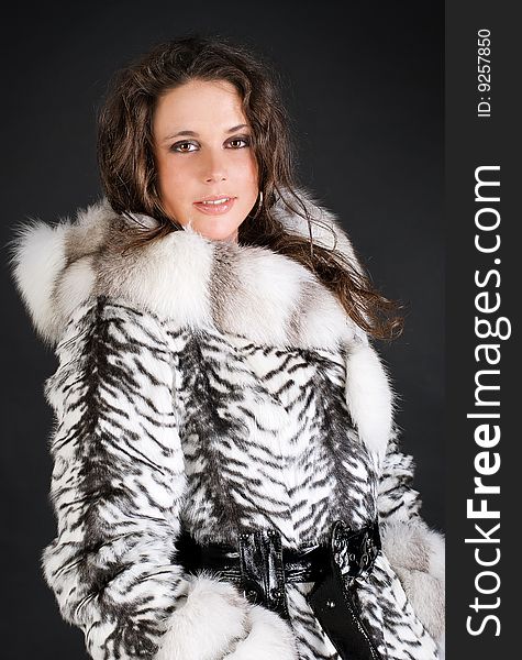 Portrait of a fashion woman in fur coat isolated over black