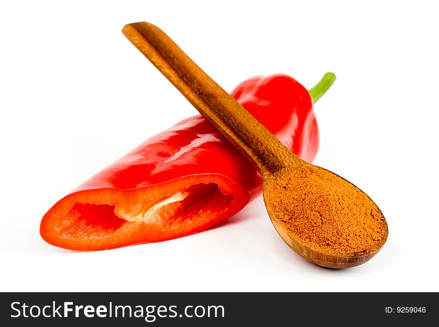 A  pod of red chile pepper and a wooden spoonful of red ground pepper on a white background. A  pod of red chile pepper and a wooden spoonful of red ground pepper on a white background