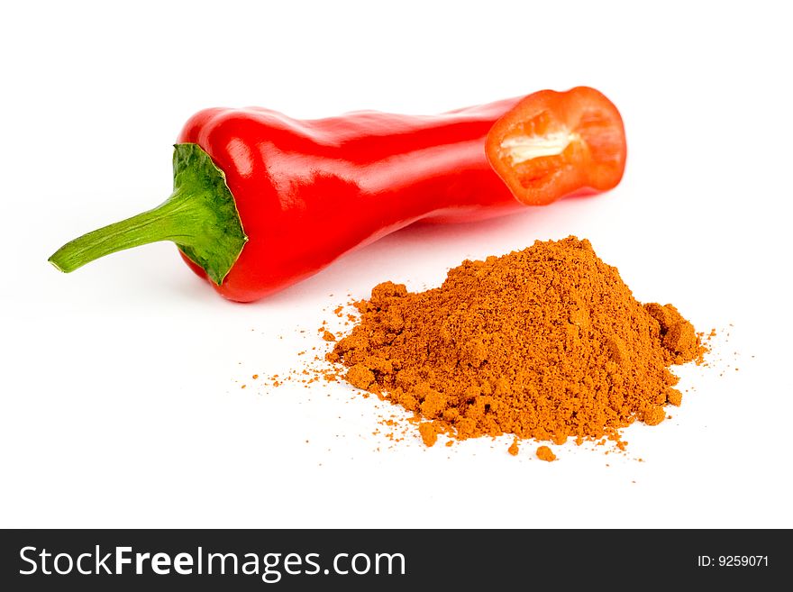 A composition of a cut pod of red pepper and a little of ground red pepper on a white background. A composition of a cut pod of red pepper and a little of ground red pepper on a white background